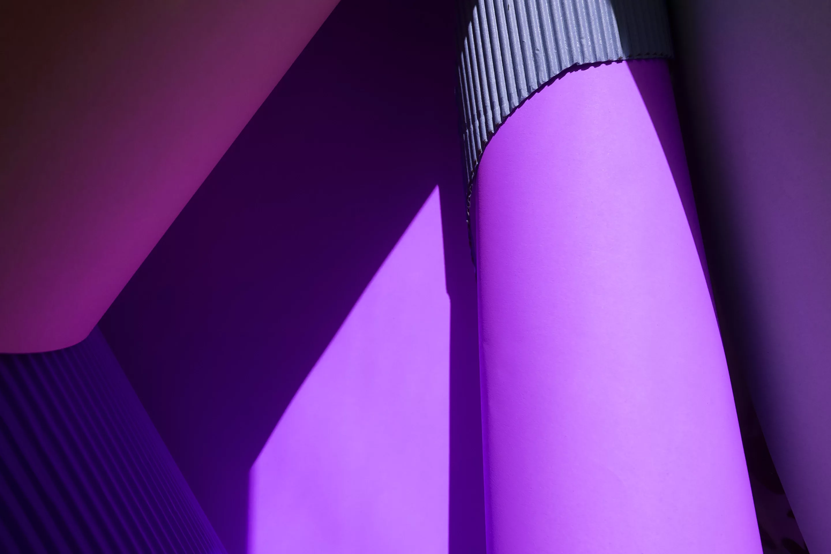 Close-up of rolled purple and corrugated paper arranged with light and shadow creating geometric shapes.