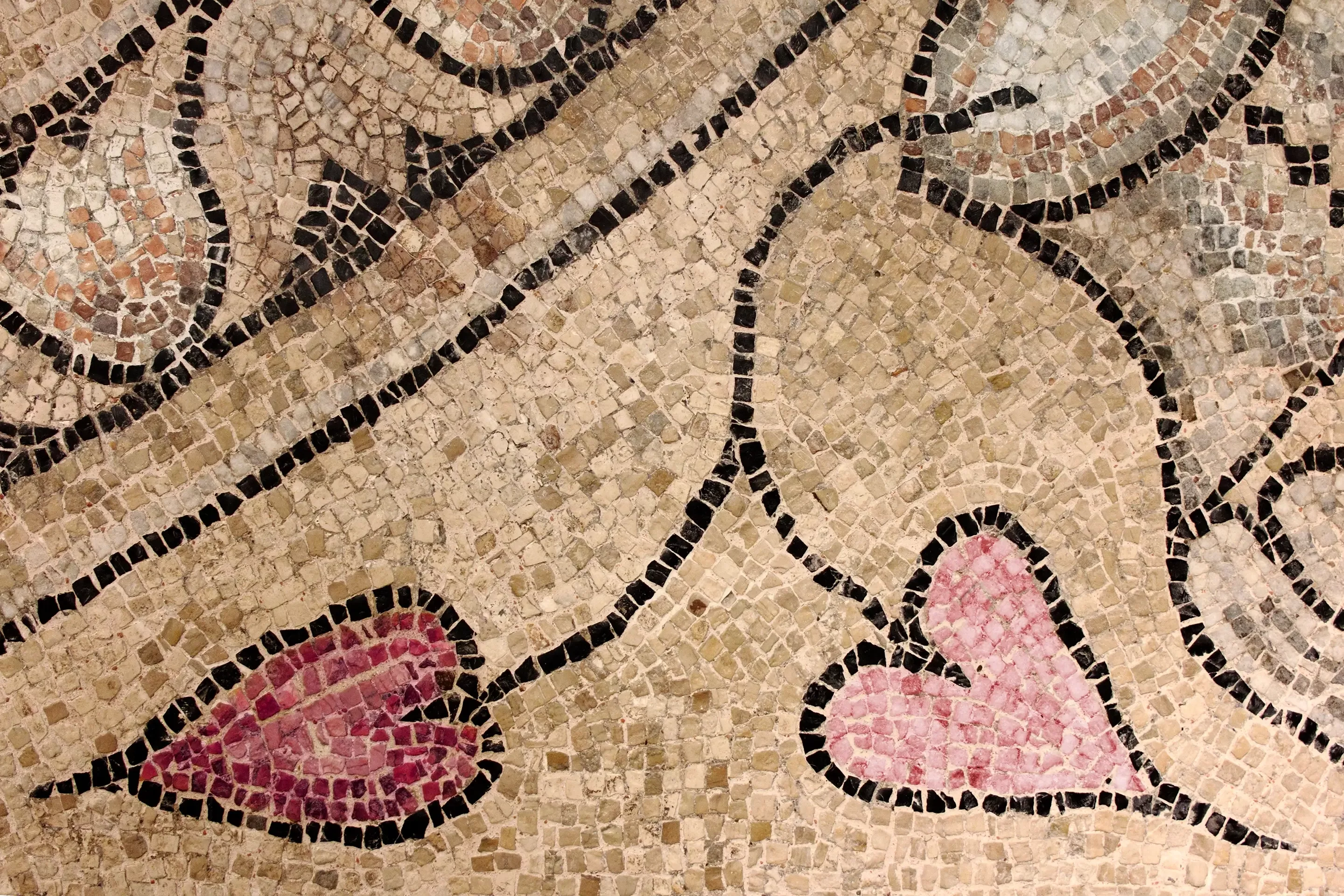 Antikes Mosaik mit zwei schwarz umrandeten rosa Herzen auf einem beigen Steinhintergrund. Geschwungene schwarze Linien schaffen ein elegantes, fließendes Bild.